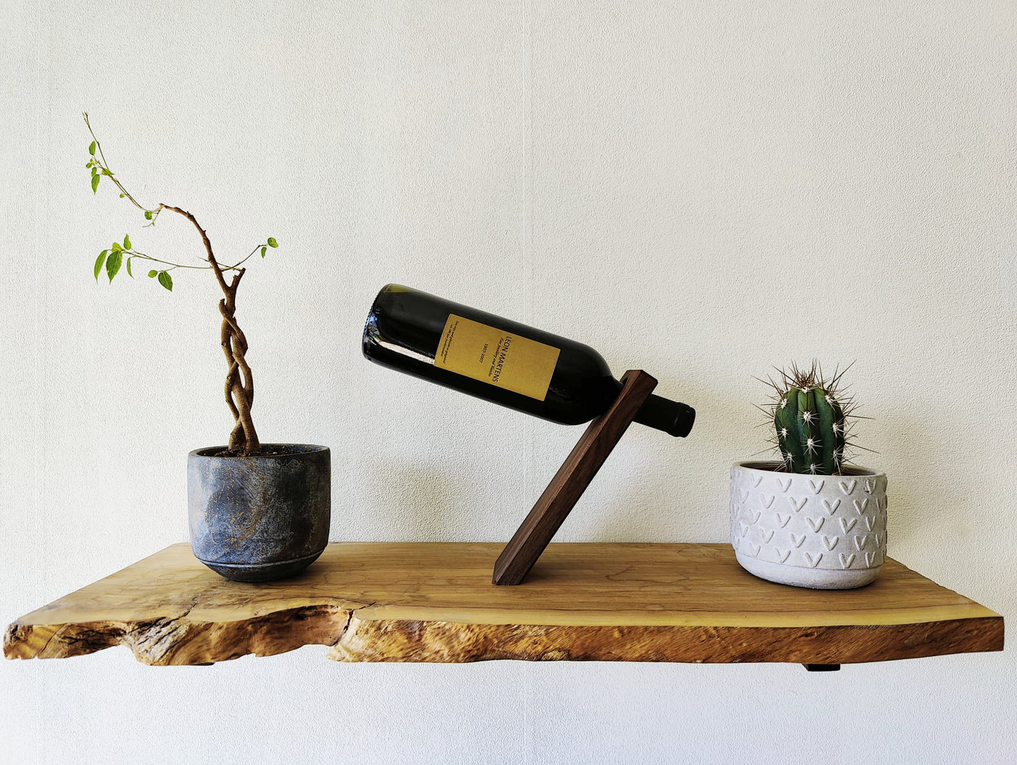 Wooden wine bottle balancer on a shelf, front view, balancing a red wine bottle at an angle